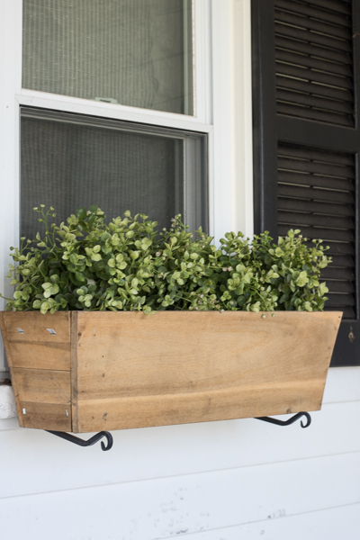 faux greenery added to planter box for spring porch